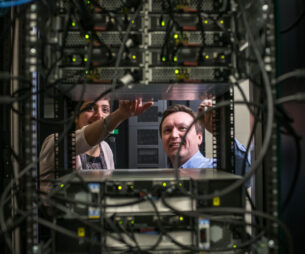 Two people working on an equipment rack in a server room with dense cables.