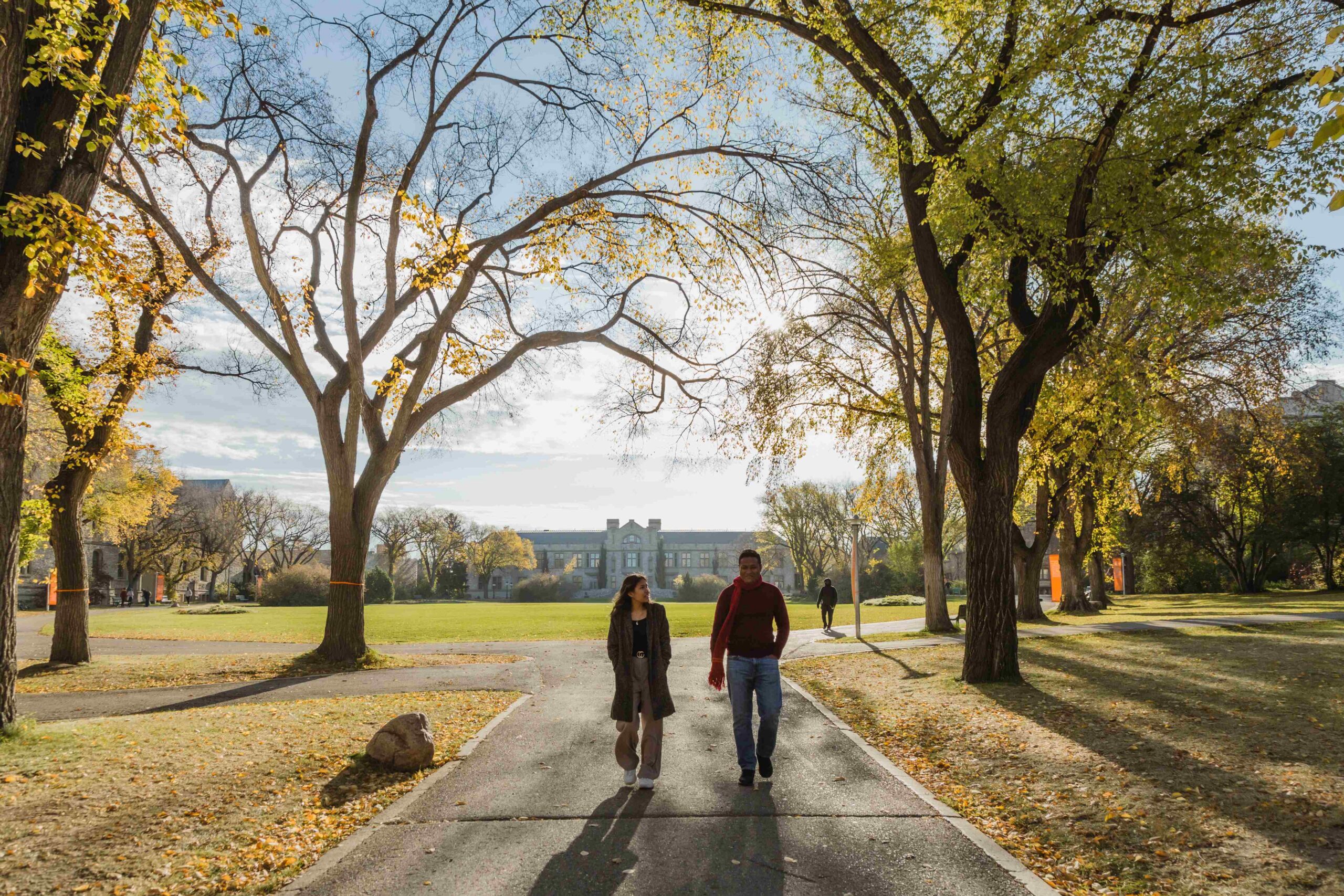 Two students walking through a campus in the fall.