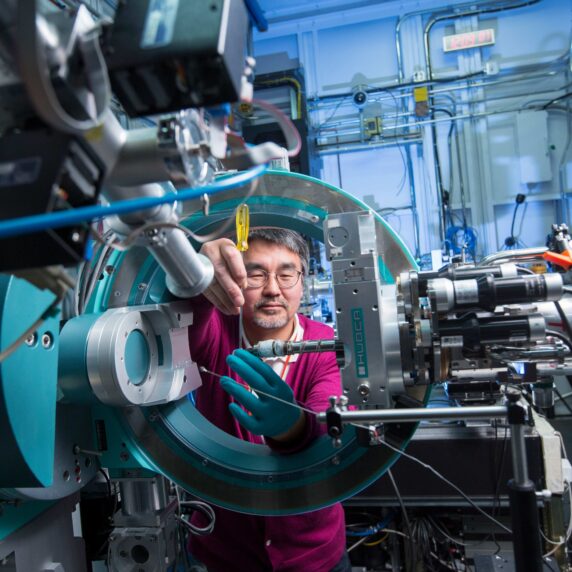 A man using a screwdriver to work on machinery in a lab.